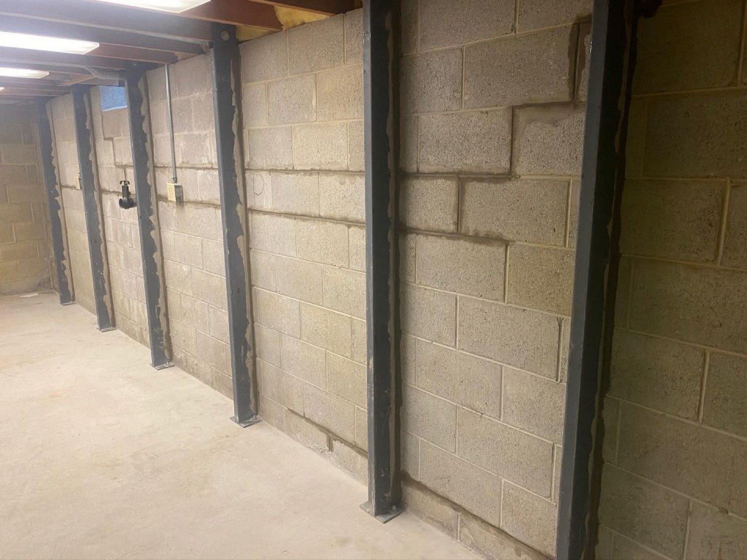 Steel I-beam wall braces on a gray block wall