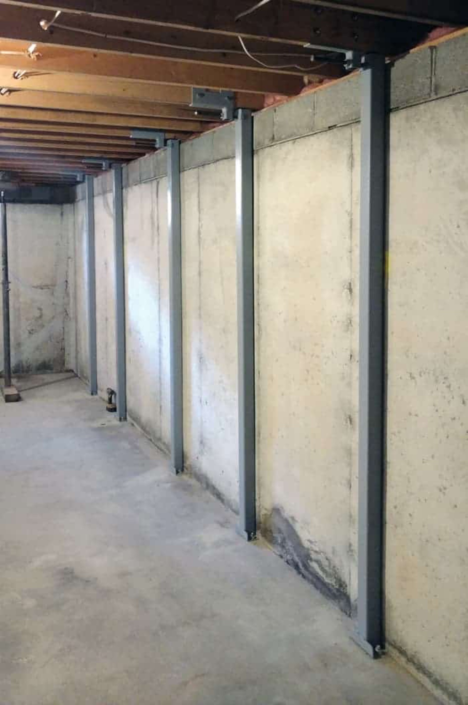 Steel I-beams bracing a poured concrete basement wall